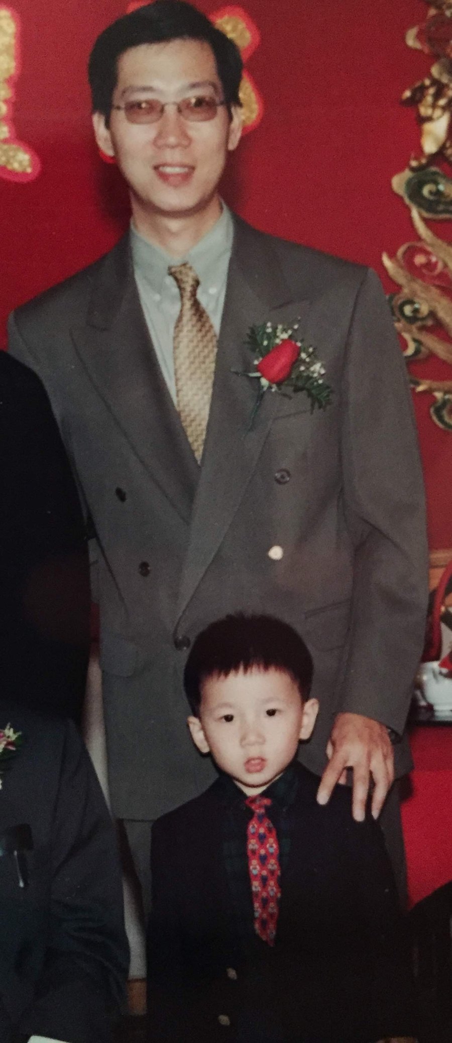 Brandon as a young boy beside his father at a family celebration